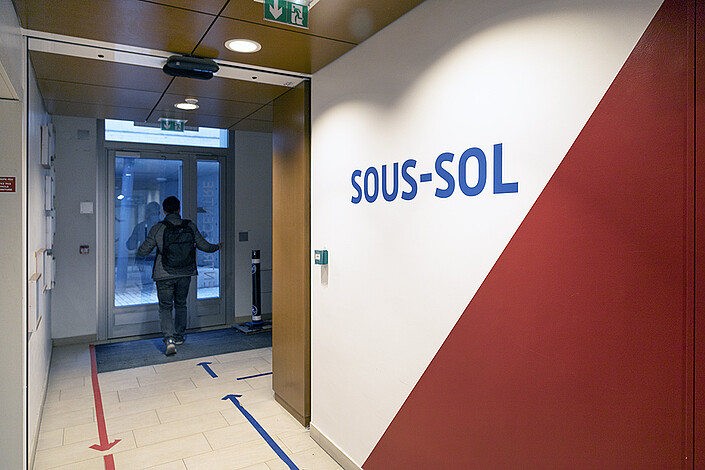 L’entrée centrale du bâtiment haut de l’Institut Le Bel avec une porte automatique et la signalétique pour les sens de circulation.